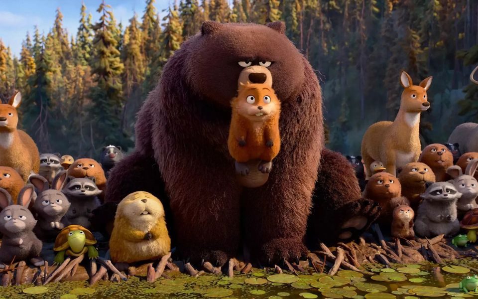 Animated still. A large brown bear holds a beaver in its mouth, surrounded by a group of woodland animals.