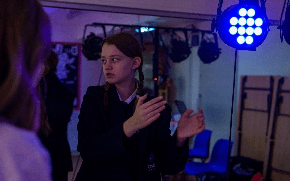 A teenager is under the stage lights in the learning space at Leeds Grand Theatre.