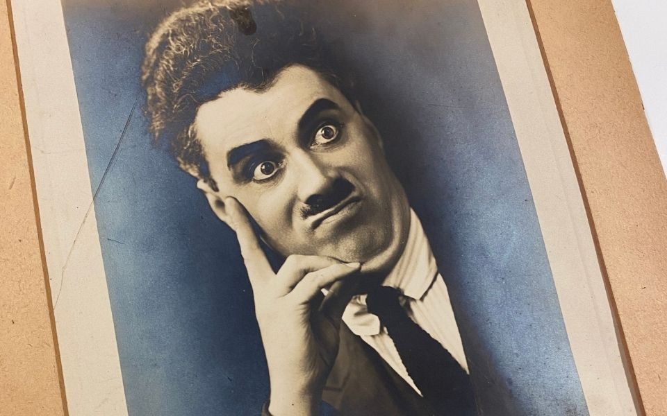 A black and white image of a man with a mustache pulling a face of faux-discomfort