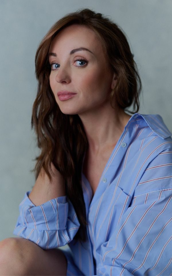 A portrait of Helen George wearing an oversized blue shirt.