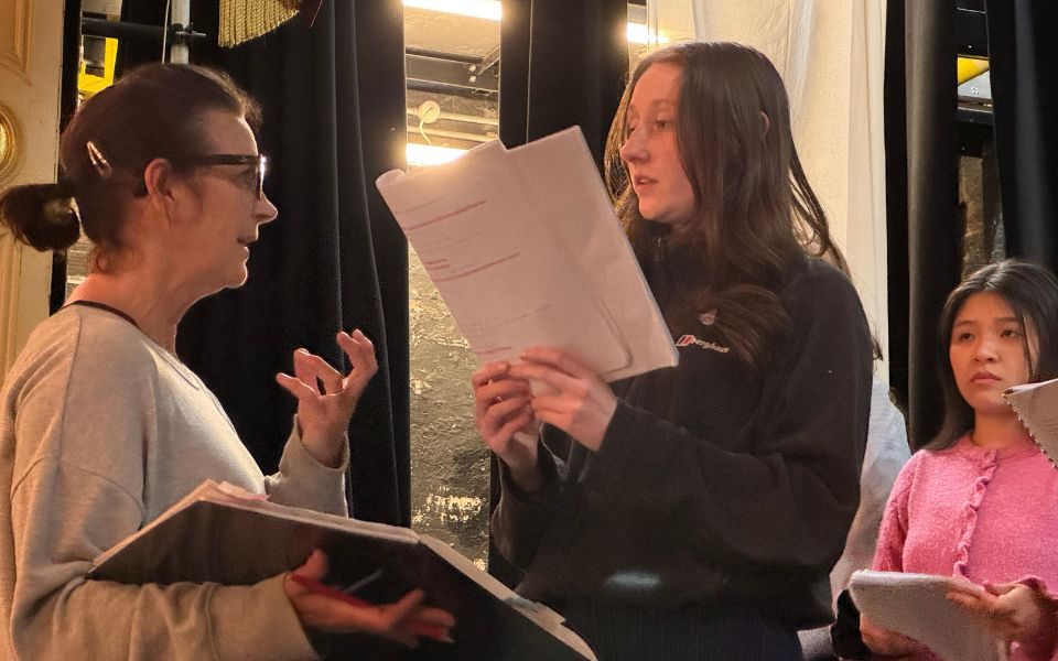 A performer holds a script as they receive notes from the director