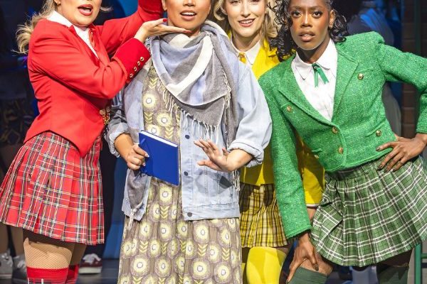 Four girls candidly pose on stage in colourful costumes.