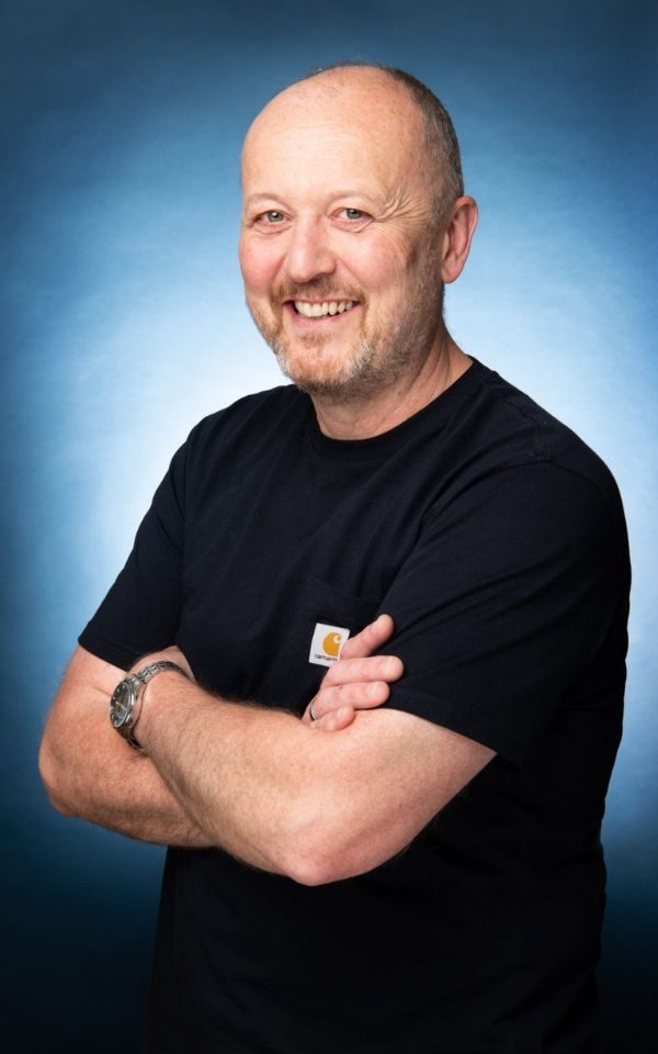A portrait of Martin Dickson smiling and folding his arms.