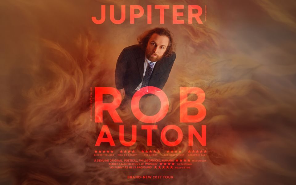 Viewed from above, Rob Auton stands in a suit and looks up at the camera, surrounded by swirling orange smoke. Text reads: Jupiter: Rob Auton.