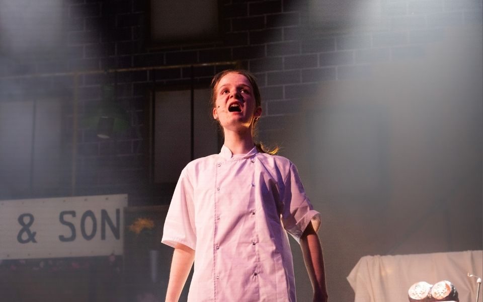 A young person singing in a dentist's uniform