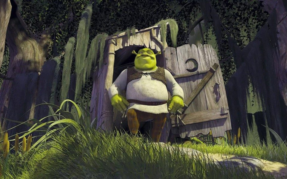Animated still of Shrek, a green ogre in a beige cloth shirt and leather tunic, emerging with a smile from a wooden shack in a swamp.
