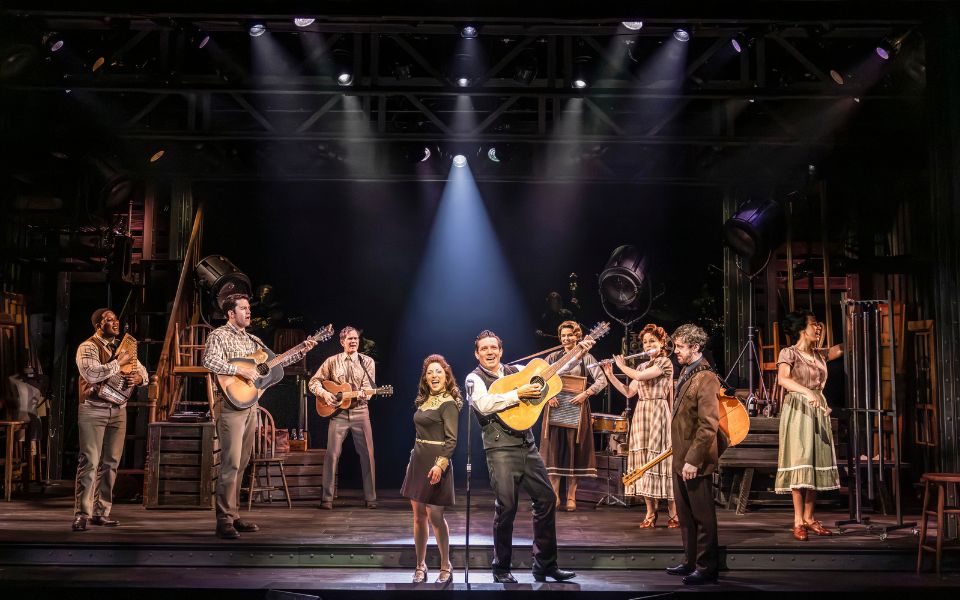 A cast of musicians playing their instruments on stage.