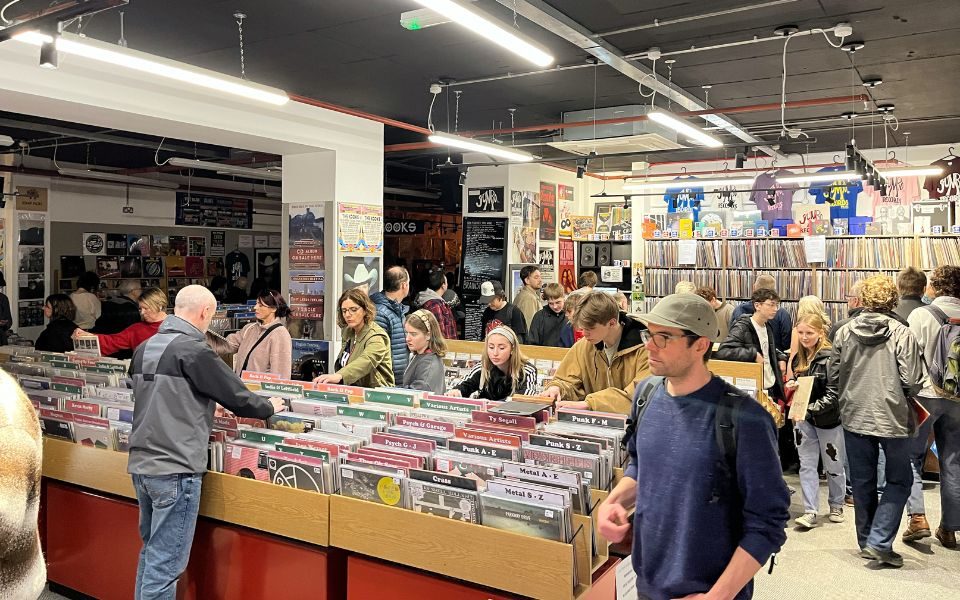 A busy record store with people sifting through shelves of vinyl.