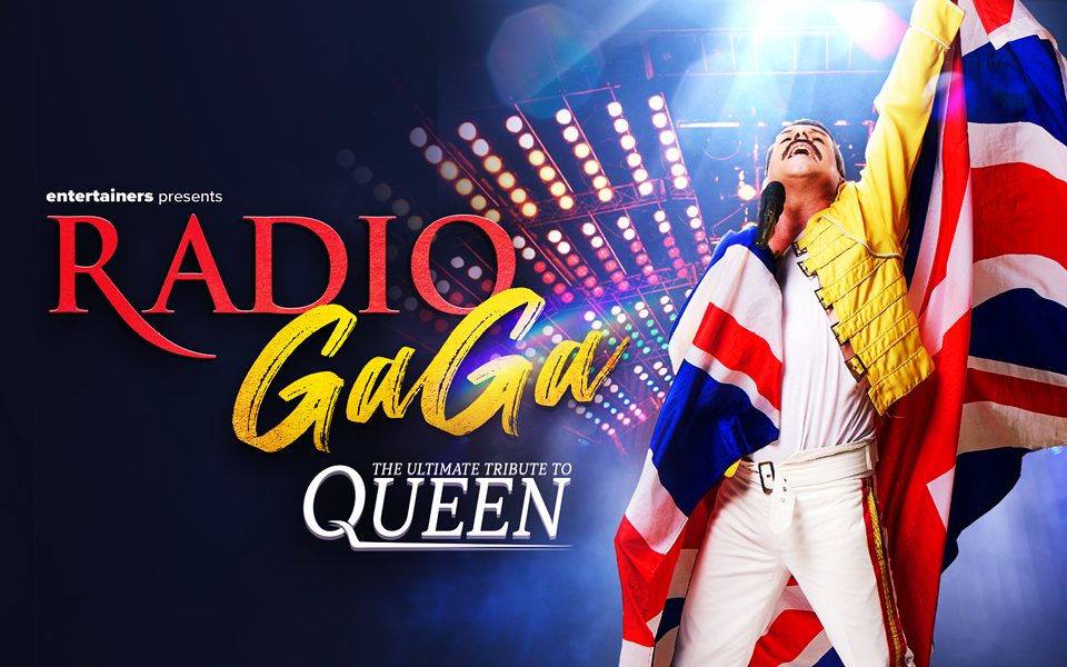 A Freddie Mercury tribute singer in a yellow jacket, white trousers and a Union flag draped over his shoulders raises a fist, in front of rows of spotlights. Text reads: Entertainers presents Radio Gaga. The ultimate tribute to Queen.