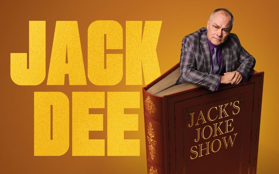Wearing a chequered suit, Jack Dee emerges from a giant red book, the title reading 'Jack's Joke Show'. Large text reads: Jack Dee.