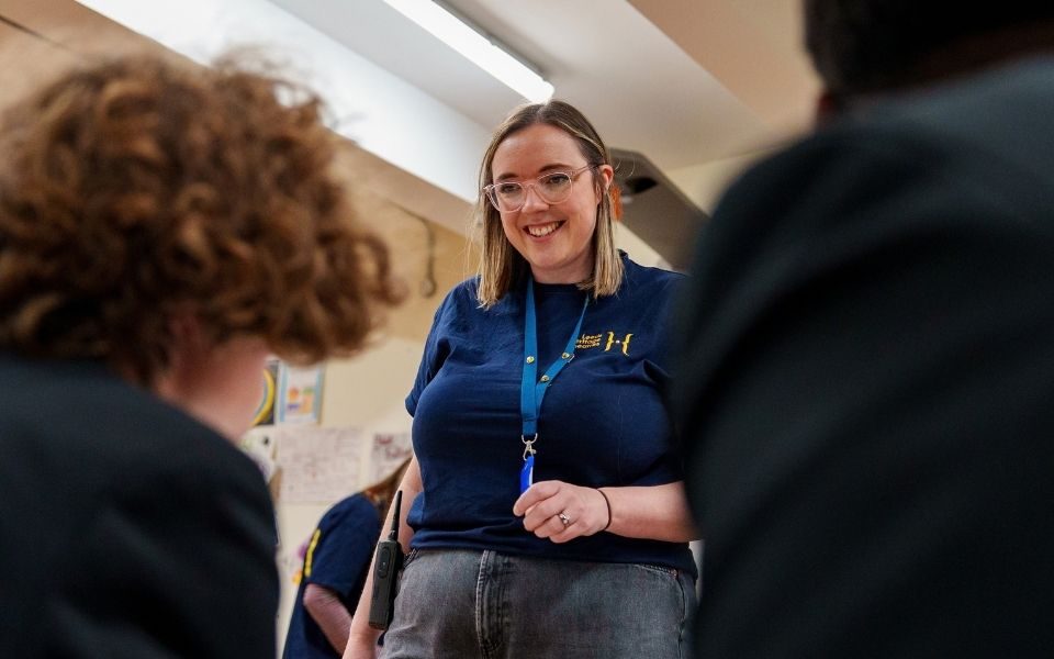 An educator in a blue shirt speaks to students