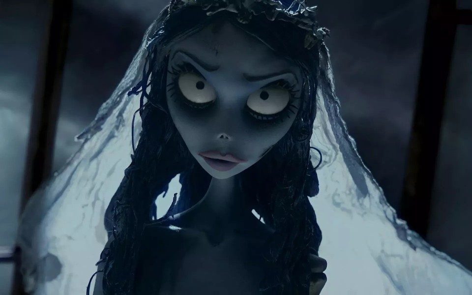 Animated still. A blue-grey character with wide eyes and long straggly hair wears a tattered veil, lit by pale moonlight.